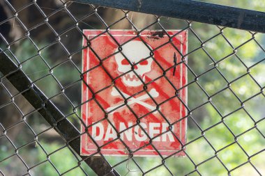 Tehlike işareti, çapraz kemik ve kafatası tel örgü çitlerin arkasında asılı. 