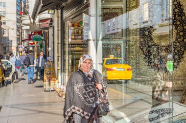 İstanbul 'da güneşli bir günde sokakta yürüyen geleneksel giysili orta yaşlı bir Türk kadını