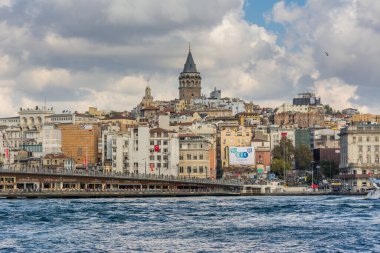 İstanbul 'daki Karaköy' de antik Galata kulesi binalarının bulunduğu Altın Boynuz Kenti, arka plandaki Boğaz 'dan bulutlu gökyüzüne uzanır.
