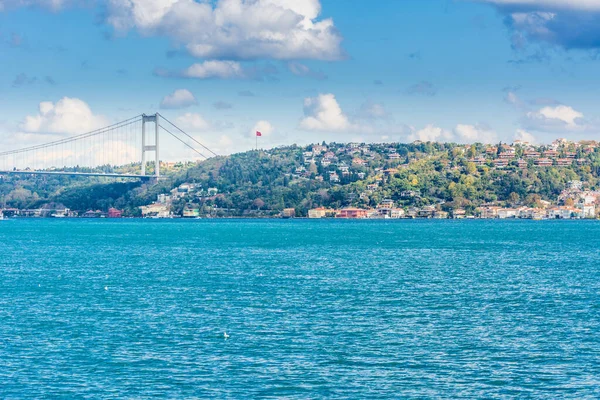 Güneşli bir günde İstanbul, İstanbul 'da arka plan bulutlu mavi gökyüzü ve mavi denizle Boğaz Boğazı' nın arka planına sahip Fatih Sultan Mehmet Köprüsü. Mavi Hindi konsepti.