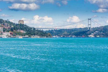 Çağdaş yapılar ve Rumeli Kalesi ve İstanbul Boğazı 'ndaki Fatih Sultan Mehmet Köprüsü güneşli bir günde arka planda bulutlu gökyüzü ile feribottan Türkiye' ye iniyor.