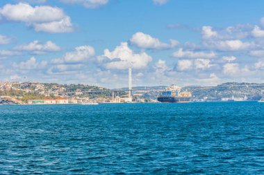 Güneşli bir günde İstanbul, Türkiye 'de arka plan bulutlu mavi gökyüzü ve mavi denizle birlikte Boğaz Boğazı' nın arka planında yer alan Boğaz Köprüsü 'nden geçen ticaret gemisi. Mavi Hindi konsepti.