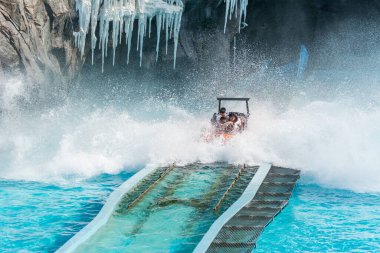 Turistler, Chimelong Okyanus Krallığı, Zhuhai, Çin 'deki parktaki piste su sıçratarak tekneye atlayıp sifonu çekiyorlar.