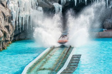 Turistler, Chimelong Okyanus Krallığı, Zhuhai, Çin 'deki parktaki piste su sıçratarak tekneye atlayıp sifonu çekiyorlar.
