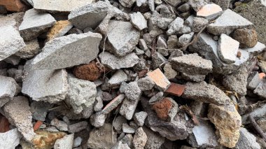 Kırık beton ve tuğla moloz parçaları, inşaat atıkları veya yıkıntıları sembolize ederek kaba bir doku oluşturuyor..