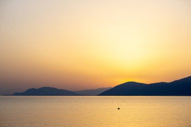 Sarı günbatımı. Güneş dağların ardında batar.