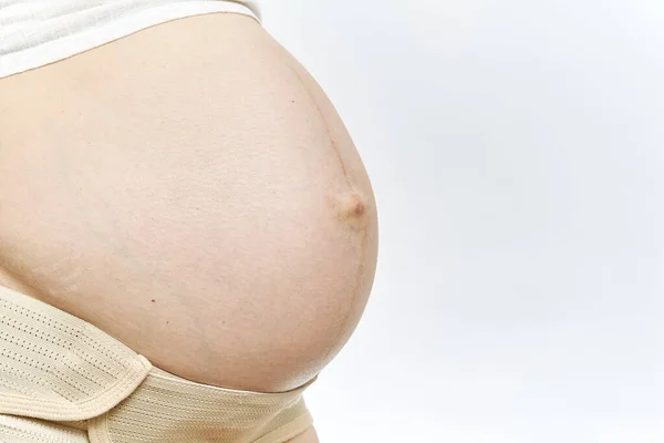 Mujeres embarazadas vientre sin rostro primer plano aislado. Cinturón de maternidad Embarazo Abdomen Apoyo Abdominal Binde. vista lateral y espacio de copia. — Foto de Stock