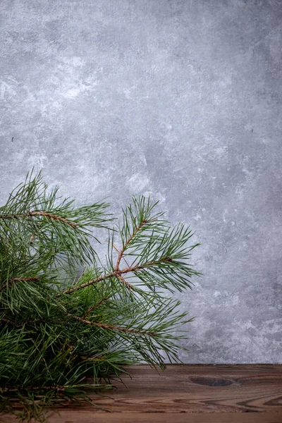 Branche de pin sur une table en bois sur un fond de béton gris. Carte Nouvel An et espace de copie. — Photo