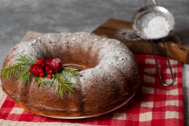 Kırmızı kareli masa örtüsünde delik olan Noel pastası. Barut süzgeci. Bulanık ve seçici odaklanma.