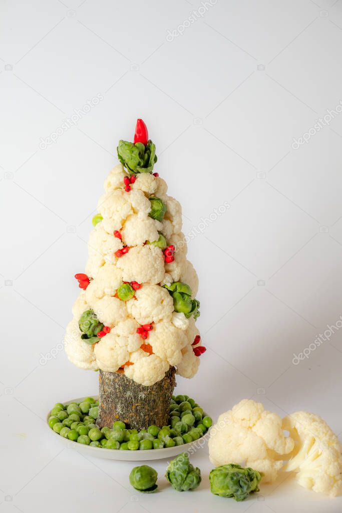 Christmas tree vegetable from cabbage on a white background. There are vegetables nearby. New year concept and copy space.