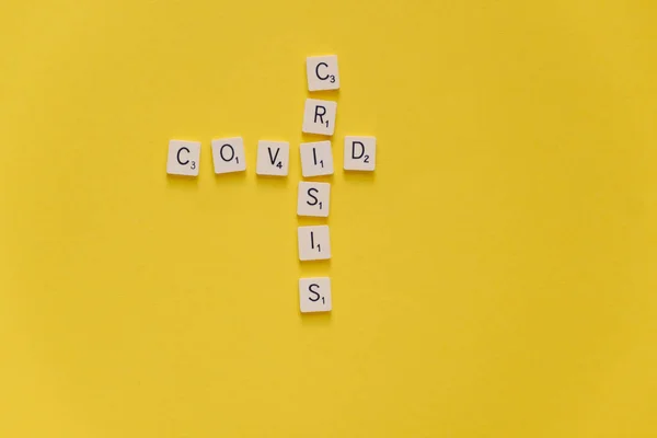 Covid Crisis. Word crossword scrabble game on a yellow background. Copy space. — Stock Photo, Image