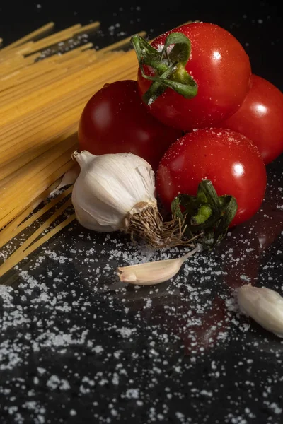 Pasta and ingredients for cooking - tomatoes, garlic, salt. Copy space and close-up. Blur and selective focus. — Foto Stock