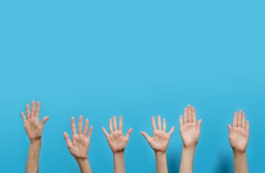 Avuç içleri açık birçok el mavi bir arka planda yükseliyor. Stüdyo çekim ve kopyalama alanı