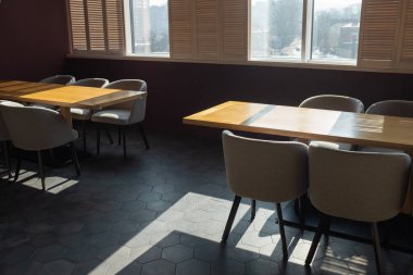 Kafenin içi güneşli ve sıcacık. Ahşap masalarda güzel doğrudan gölgeler. Tecrit sırasında boş kafe.