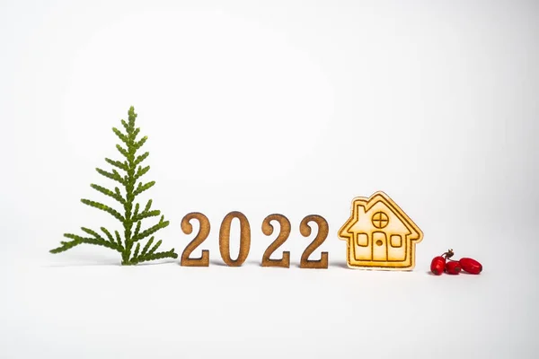 Mutlu yıllar 2022. 2022 numara tahtadan yapılmıştır. Minimalizm ve kopyalama alanı. Beyaz arka planda küçük bir ev ve Noel ağacı — Stok fotoğraf