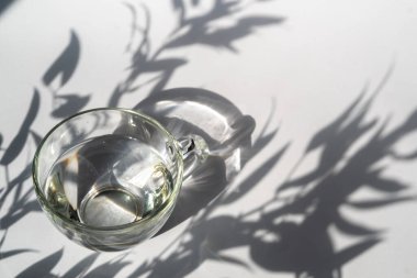 Soyut açılış arkaplanı ve su dolu cam bardak. Arka plan için doku. Beyaz arkaplanda gölge deseni