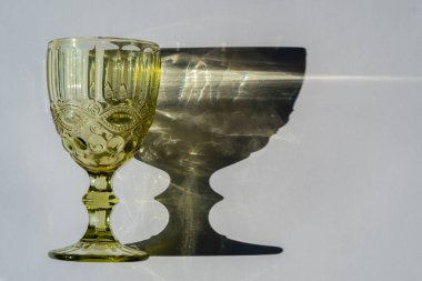 Beyaz arka planda yeşil şarap kadehi ve gölgesi.. 