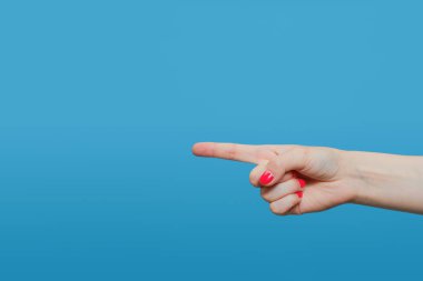 Başparmağını kaldırarak buna benzer bir işaret yapan bir kadın. Mavi arka planda kırmızı jel cilası manikürlü bir kadın eli. Boşluğu kopyala