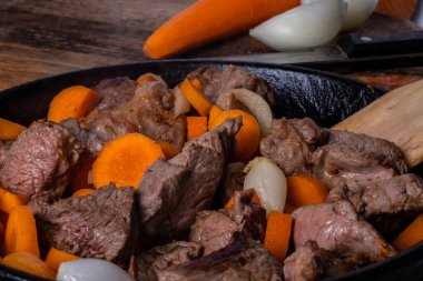 Kızartma tavasında sığır filizlenme süreci. Çiğ et, havuç ve soğan. Yavaş yemek konsepti 