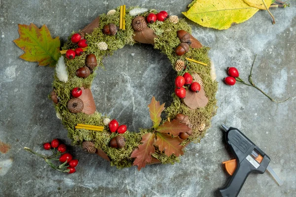 Gri arka planda doğal malzemelerden elde yapılan sonbahar çelengi. Sonbahar evi dekorasyon konsepti. Çelenk yapmak için DIY materyalleri.