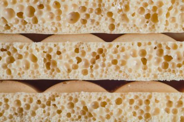 Karamelli çikolataların iki sıra halinde makro yakın çekimi. Havadar baloncuklu gözenekli doku, tatlı markalaşma, paketleme ve gurme şekerleme tasarımı için mükemmel.. 