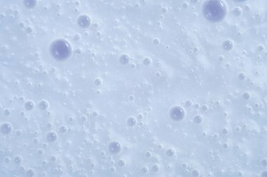 Close-up of light blue surface with scattered translucent bubbles of varying sizes. Gentle, pastel look with a clean, modern feel. Soft lighting and minimal texture 