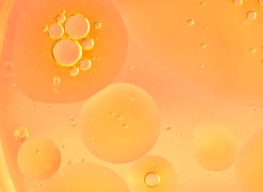 Orange abstract bubbles in liquid, macro. Different-sized clear bubbles float on a saturated orange background. Clean, warm composition, horizontal format, bright and modern