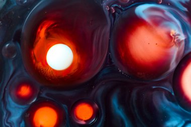Abstract macro photo of colored bubbles forming dynamic circles in red, orange, blue and white liquid. Sci-fi, energetic visual, glowing highlights. Design for artistic, science, creative backgrounds 