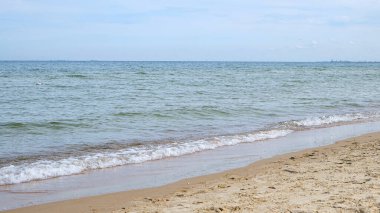 Serene coastline with light sand and soft transparent waves washing ashore, clear sky creates open, minimalist seascape. Summer vacation, relaxation, ideal for banner with copy space. 