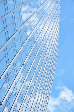 Keskin mimari çizgilerle gökyüzünü yansıtan uzun cam bina, parlak ve temiz bir atmosfere sahip modern bir kentsel estetik yaratıyor.