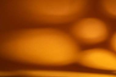Yumuşak oval bokeh şekilleri ve nazik gradyanlarıyla çözünmüş sıcak altın turuncu arka plan, şenlikli, lüks veya iyi tasarımlar için ideal minimum soyut doku kopya alanı ile. 