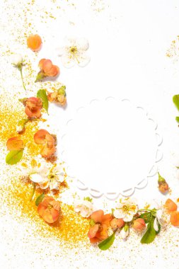 Yeşil yapraklar ve safran tozu ile portakal ve beyaz bahar çiçeklerinin dikey bileşimi beyaz arka planda kısmi dairesel bir çerçeve oluşturuyor, tebrik kartı ve kozmetik pankart için ideal. 