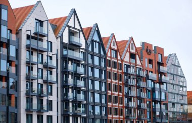 Gdansk, Polonya, 13 Eylül 2025. Gdansk 'ta nehir kenarında camdan balkonları olan modern gable apartman binaları, tekrar eden çatı ve pencereleri olan çağdaş mimari.
