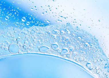 Kabarcıkları ve pürüzsüz yüzeyi olan mavi sıvının makro fotoğrafı. Temiz kompozisyon saflığı, suyu ve bilimsel veya kozmetik kavramları çağrıştırıyor, arka plan ve markalaşma için ideal..