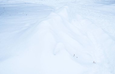 Düşük açıyla çekilen geniş beyaz alanda taze kar yağışı zirvesi. Serin mavi tonlar, pürüzsüz toz dokusu, ince gölgeler. Metin kaplamaları için kenarlarda çoğalt.