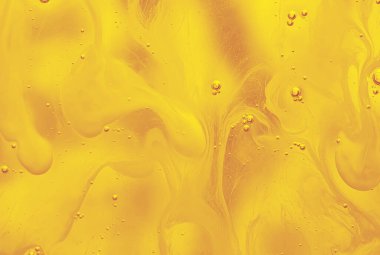 Sarı sıvı, pürüzsüz akış şekilleri ve küçük hava kabarcıkları olan soyut makro fotoğraf. Arkaplan, bilim, yaratıcılık ve modern tasarım kavramları için uygun canlı organik doku..