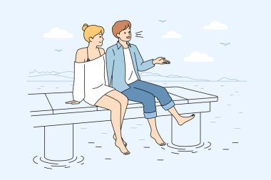 Okyanus kıyısında oturan bir çift, tanımlanamayan bir ırk, takım elbiseli bir adam beyaz elbiseli bir kadına el sallıyor, çıplak ayaklarıyla suyun üzerinde sallanıyor.,