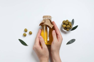 Beyaz arka planda lezzetli zeytinyağı ve bir şişe zeytinyağı tutan kadın, yakın plan.
