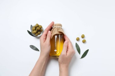 Kadın hafif arka planda zeytinyağı ve zeytin şişesi tutuyor.
