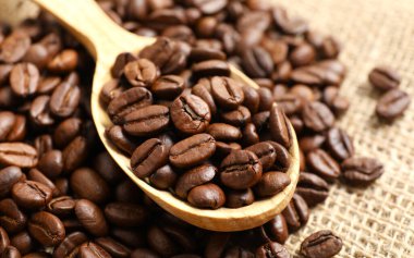 Beyaz fincanda kahve çekirdeği, ahşap arka planda.