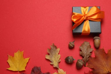 Hediye kutusu ve düşmüş yapraklar dizayn için alanı olan kırmızı bir zemin üzerinde.