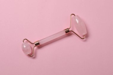 Yüz masajı aleti. Kuvars yeşim taşı, pembe arka planda..