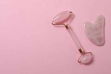 Yüz masajı aleti. Kuvars yeşim taşı, pembe arka planda..