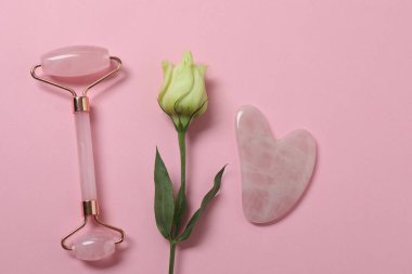 Yüz masajı aleti. Kuvars yeşim taşı, pembe arka planda..