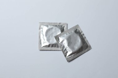 Beyaz zemin üzerinde bir prezervatifin yakın plan, kare ve dikdörtgen paketler beyaz arkaplan üzerinde (yetişkin içeriği) - kırpma yolu.