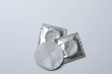 Beyaz zemin üzerinde bir prezervatifin yakın plan, kare ve dikdörtgen paketler beyaz arkaplan üzerinde (yetişkin içeriği) - kırpma yolu.