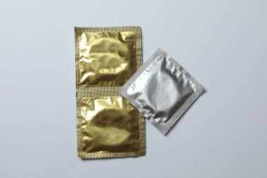 Beyaz zemin üzerinde bir prezervatifin yakın plan, kare ve dikdörtgen paketler beyaz arkaplan üzerinde (yetişkin içeriği) - kırpma yolu.