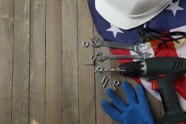 ABD 'de İşçi Bayramı' nı sembolize eden ahşap yüzey üzerindeki iş eldivenleri, aletler ve Amerikan bayrağı.