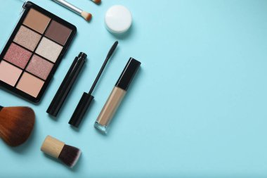 Mavi arka planda güzellik ürünleri. Kozmetik palet, fırça, krem ve ruj. Üst görünüm.