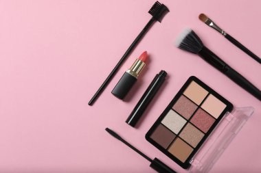 Pembe arka planda kozmetik ürünler. Kozmetik palet, fırçalar, kremler ve rujlar. Üst görünüm.